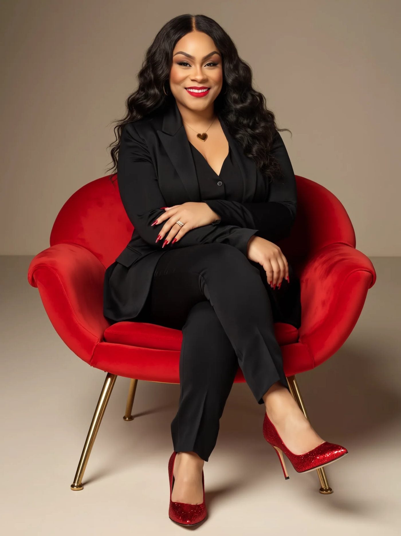 ALowe McCants in a black suit seated in a red chair